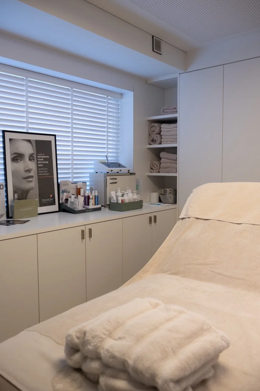 Behandeltafel met witte plaid en skincareproducten in de cabine